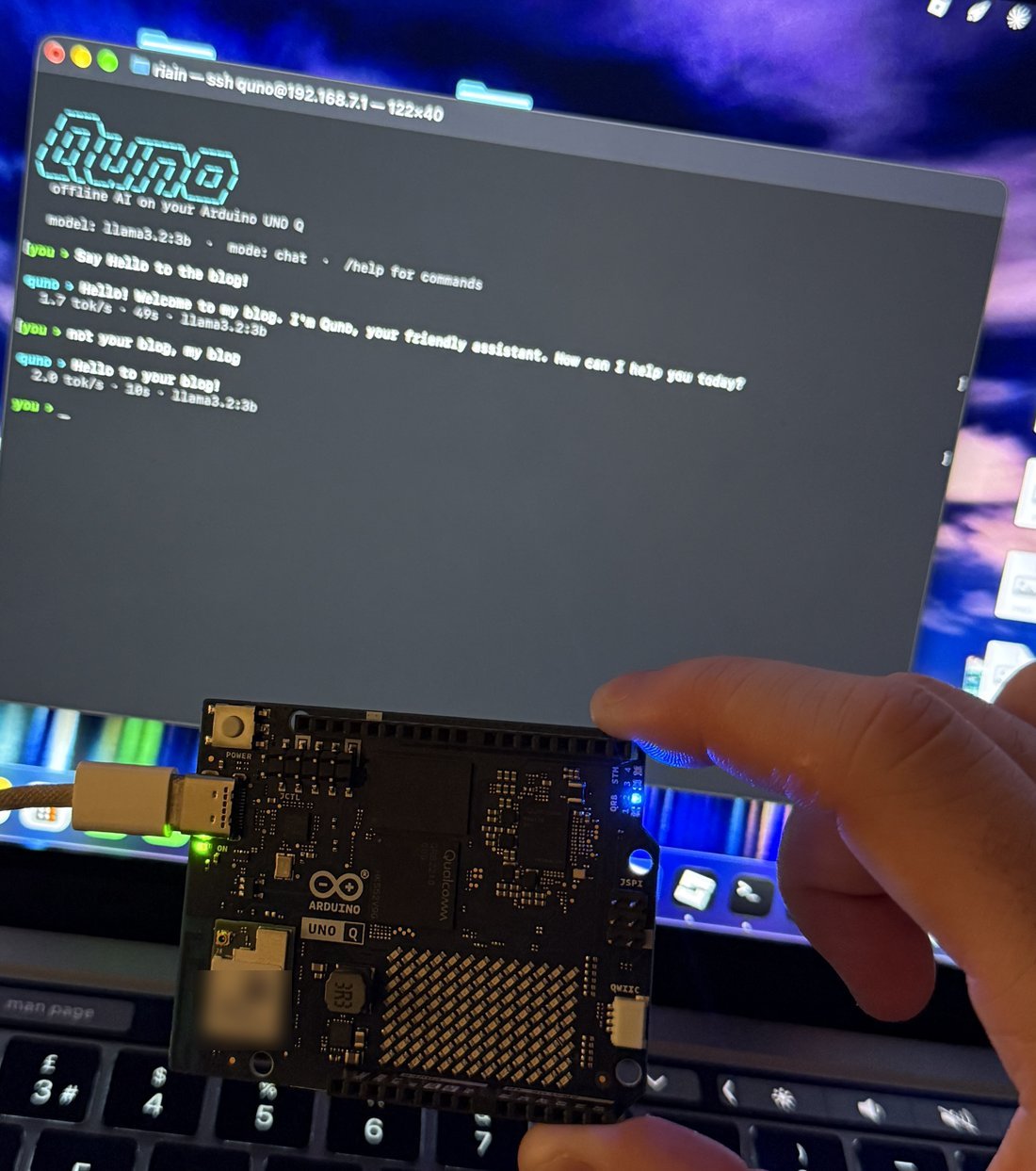 The Arduino UNO Q plugged into a MacBook by USB, with the Quno chat open in the terminal behind it
